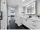 Bright bathroom featuring white cabinets, black hardware, marble countertops, and modern lighting at 100 Oakmont Ln # 802, Belleair, FL 33756