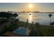 A golden sunrise over a swimming pool with palm trees and a view of the bay at 100 Oakmont Ln # 802, Belleair, FL 33756