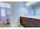 Bathroom with double sinks and dark cabinets, and view into a bedroom with natural light at 11606 Quiet Forest Dr, Tampa, FL 33635