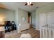 Bedroom with neutral walls, ceiling fan, white dresser and crib, plus a desk and office chair at 11606 Quiet Forest Dr, Tampa, FL 33635