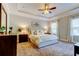 Serene main bedroom with tray ceiling, ceiling fan, soft carpet, and bright windows with elegant drapes at 11606 Quiet Forest Dr, Tampa, FL 33635