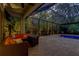 Outdoor covered patio with cozy seating and a view of the screened pool and landscaping at 11606 Quiet Forest Dr, Tampa, FL 33635