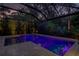 Evening view of the screened pool with tanning ledge and travertine decking at 11606 Quiet Forest Dr, Tampa, FL 33635