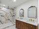 Bathroom featuring double sinks, vanity and a walk-in shower with marble tile at 11764 Pinedale Ave, Seminole, FL 33772