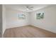 A bedroom with a ceiling fan, new light wood-look flooring, and two windows at 11764 Pinedale Ave, Seminole, FL 33772
