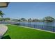 Waterfront view from the backyard with green lawn, black iron fence, dock and neighboring properties at 1185 36Th Ne Ave, St Petersburg, FL 33704