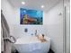 Relaxing bathroom with a soaking tub, ocean art, and textured white tile at 1310 Gulf Blvd # 6C, Clearwater Beach, FL 33767