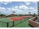 Outdoor tennis court surrounded by tropical landscaping, featuring a green and red surface at 1310 Gulf Blvd # 6C, Clearwater Beach, FL 33767