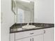 Bathroom features granite countertop, white cabinets and faucet, mirror reflects entryway door at 1624 Lullwater Ln, Lutz, FL 33549