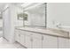 Bathroom with double sinks, white cabinets and a vanity mirror adorned with colorful glass beads at 1624 Lullwater Ln, Lutz, FL 33549