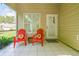 Cozy screened porch with two red Adirondack chairs, bright sunflower pillows, and outdoor access at 1624 Lullwater Ln, Lutz, FL 33549