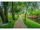 Picturesque view of a sidewalk and wooden bridge surrounded by trees, green lawns, and water at 1624 Lullwater Ln, Lutz, FL 33549
