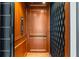 A private residential elevator features wood paneled interior and a black accordion gate at 16365 Redington Dr, Redington Beach, FL 33708