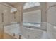 Large soaking tub with tile surround, sunny window, and walk-in shower for ultimate relaxation at 16367 Ashington Park Dr, Tampa, FL 33647
