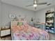 Cozy bedroom with a ceiling fan, pink bedspread, and a desk area with storage shelves at 16367 Ashington Park Dr, Tampa, FL 33647