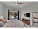 Bright bedroom featuring a ceiling fan, TV, mirror, and sliding door access to the outdoor living space at 16367 Ashington Park Dr, Tampa, FL 33647