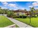 Community building with tropical landscaping, bright green lawn, and accessible parking at 1701 Pinehurst Rd # 9G, Dunedin, FL 34698