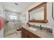Bathroom featuring a tiled walk-in shower, granite vanity, and large mirror at 1707 Hibiscus S Cir, Oldsmar, FL 34677