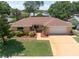 Front exterior view showcasing the landscaping and a paved driveway leading to an attached two-car garage at 1707 Hibiscus S Cir, Oldsmar, FL 34677