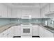 A kitchen featuring modern appliances, white cabinets and light blue backsplash at 1859 Shore S Dr # 202, South Pasadena, FL 33707