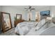 Well-lit bedroom with a ceiling fan, two dressers, a soft rug, and views of the ensuite bathroom at 19183 Coastal Shore Ter, Land O Lakes, FL 34638