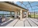 Spacious screened patio with ample seating, ceiling fan, and views of the beautiful backyard and lake at 19183 Coastal Shore Ter, Land O Lakes, FL 34638