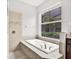 Bathroom featuring a relaxing soaking tub with tiled surround and a view from the large window at 20106 Bending Creek Pl, Tampa, FL 33647