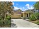 Inviting home featuring a tan exterior, two-car garage, and well-maintained lawn and landscaping at 20106 Bending Creek Pl, Tampa, FL 33647