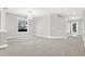 Expansive living room with plush gray carpet, neutral walls, and large windows at 20106 Bending Creek Pl, Tampa, FL 33647
