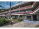 Three-story building featuring multiple residences, red accent roofing, and neatly landscaped walkway at 2073 Denmark St # 9, Clearwater, FL 33763