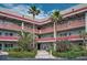 Condominium building exterior featuring red trim, balconies, tropical landscaping, and palm trees at 2073 Denmark St # 9, Clearwater, FL 33763