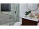 A modern bathroom with a marble tiled shower, gold fixtures, a round mirror, and a stylish vanity sink at 2219 Thrace St, Tampa, FL 33605
