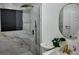 A modern bathroom featuring a glass-enclosed shower with marble tile, gold fixtures and a stylish round mirror at 2219 Thrace St, Tampa, FL 33605