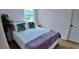 Cozy bedroom with natural light, white walls, light wood floors and a bed with stylish pillows and a pink accent at 2219 Thrace St, Tampa, FL 33605