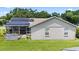 A view of the home's back exterior with solar panels, a screened in porch, and a manicured lawn at 22852 Fern Ct, Land O Lakes, FL 34639