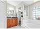 Bright bathroom featuring wood vanity, glass shower, and soaking tub with tiled surround, and plenty of natural light at 22852 Fern Ct, Land O Lakes, FL 34639