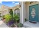 Home's front entry featuring a blue door with sidelight windows and colorful landscaping at 22852 Fern Ct, Land O Lakes, FL 34639