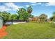 The big backyard features a large green lawn, fenced perimeter, and other greenery at 2303 E Osborne Ave, Tampa, FL 33610