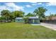 Home exterior with green paint and metal roof, with a green lawn and palm tree at 2303 E Osborne Ave, Tampa, FL 33610