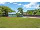 Lawn view of the home's exterior, with green paint and black-fenced backyard at 2303 E Osborne Ave, Tampa, FL 33610