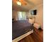 Cozy bedroom with wood floors, neutral walls, TV, and sliding glass door to balcony at 2625 State Road 590 # 913, Clearwater, FL 33759
