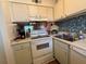 Practical kitchen featuring white appliances, a charming backsplash, and plenty of storage options at 2625 State Road 590 # 913, Clearwater, FL 33759