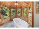 Luxurious bathroom with a stand alone tub, wood paneled walls, and natural lighting at 3112 W Wallcraft Ave, Tampa, FL 33611