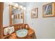 Bathroom with a vessel sink atop a wooden cabinet, decorative mirror, designer faucet, and unique lighting fixtures at 3112 W Wallcraft Ave, Tampa, FL 33611