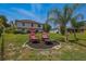 A spacious backyard featuring a fire pit and an outdoor seating area under palm trees at 31747 Loch Aline Dr, Wesley Chapel, FL 33545