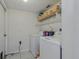 A well-lit laundry room with washer, dryer, storage shelf, and tiled flooring at 31747 Loch Aline Dr, Wesley Chapel, FL 33545