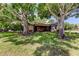 Well-manicured front yard with mature trees and a screened patio enhancing the home's curb appeal at 3410 Briarwood Ln, Safety Harbor, FL 34695