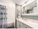 Bright bathroom with a white vanity, large mirror, and shower with decorative blue shower curtain at 3455 Countryside Blvd # 101, Clearwater, FL 33761