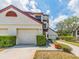 Inviting townhouse exterior with a one-car garage and lush landscaping, under a bright sky at 3455 Countryside Blvd # 101, Clearwater, FL 33761