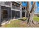 Exterior view of a two-story apartment building with screened in patios and mature tree at 4032 Cortez Dr # A, Tampa, FL 33614